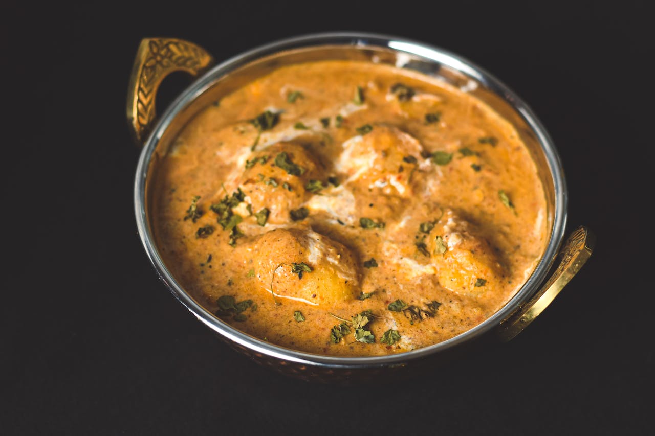 gallery-3 Flavorful dum aloo curry served in a traditional kadai, perfect for Indian cuisine lovers.